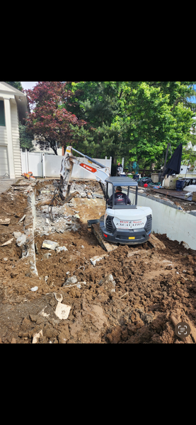 A man, skid steer, and compactor on a gravel surface, preparing a yard area.
