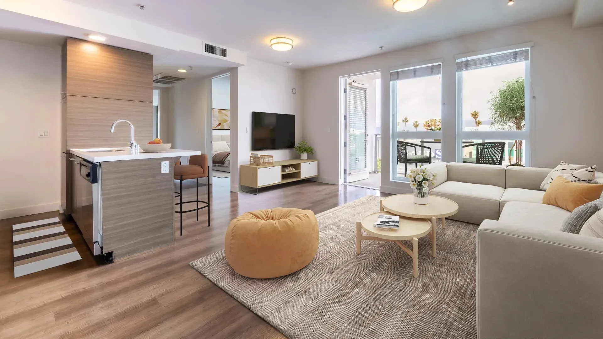 Modern living room and kitchen area with a sectional sofa, coffee tables, TV, and island.