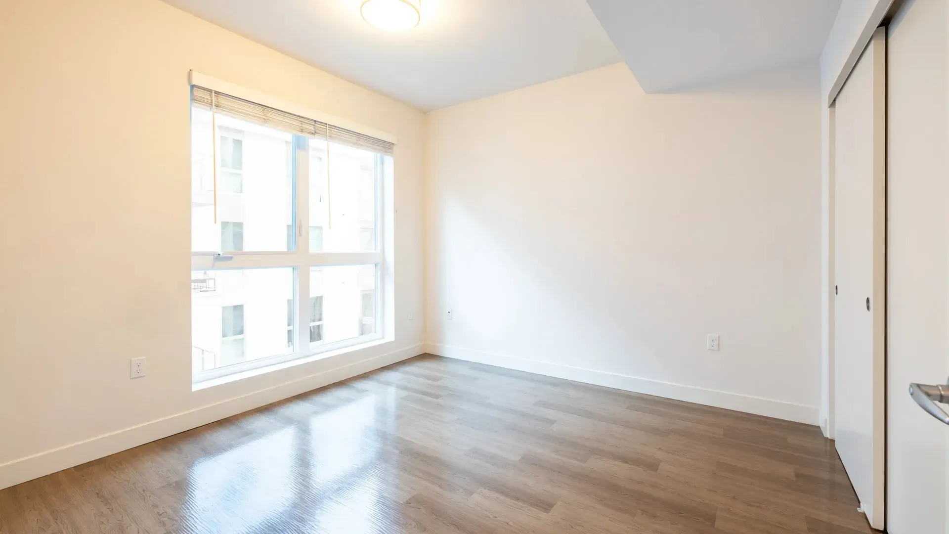Empty bedroom with a large window and a closet.