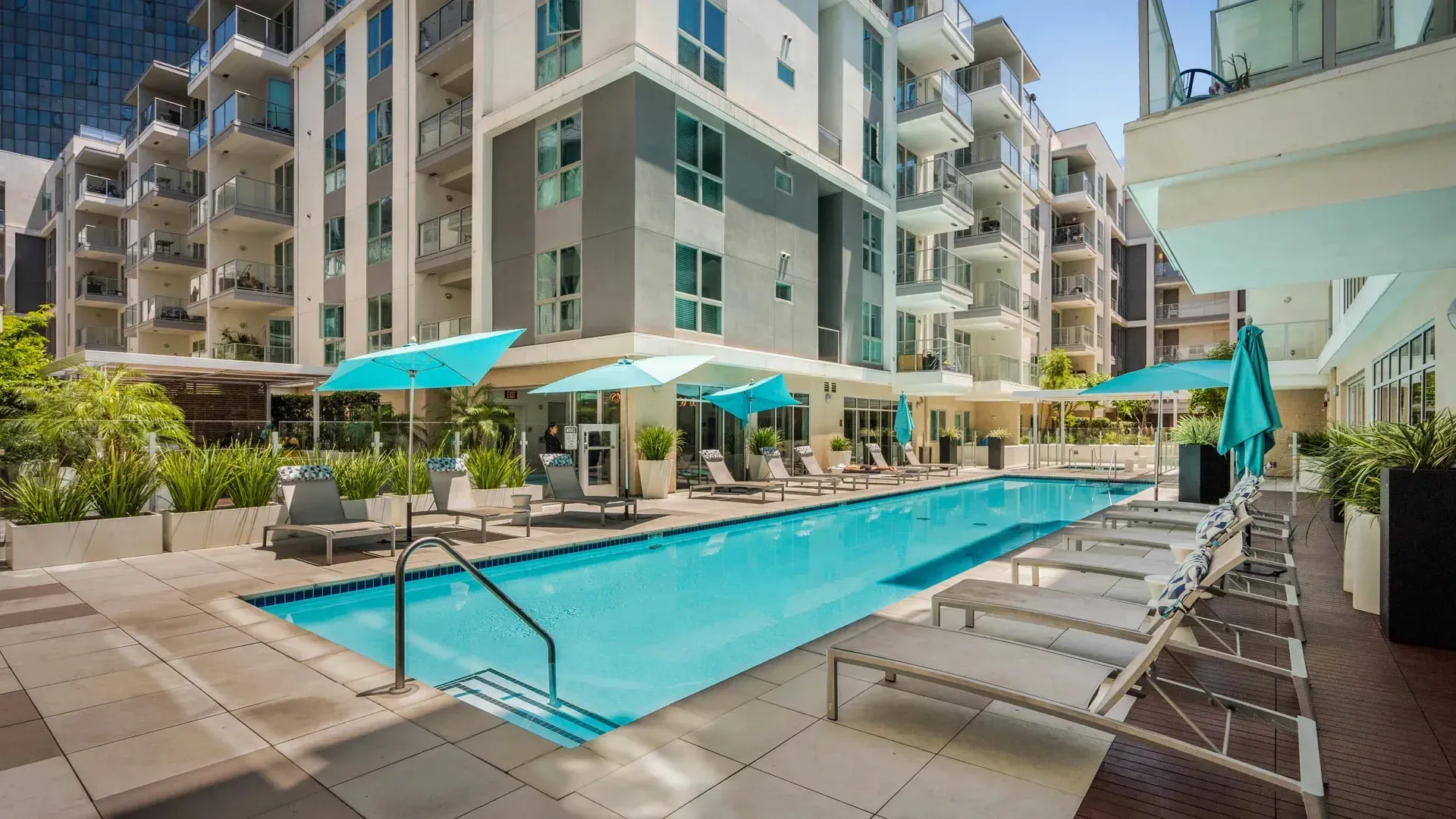 Resort-style outdoor swimming pool with lounge chairs and umbrellas.