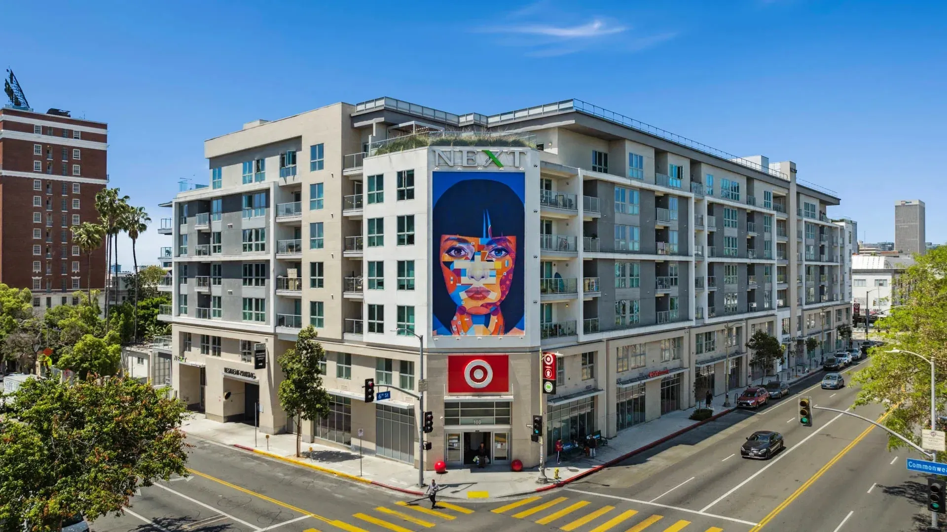 The exterior of the NEXT apartment building with a large mural of a woman's face.