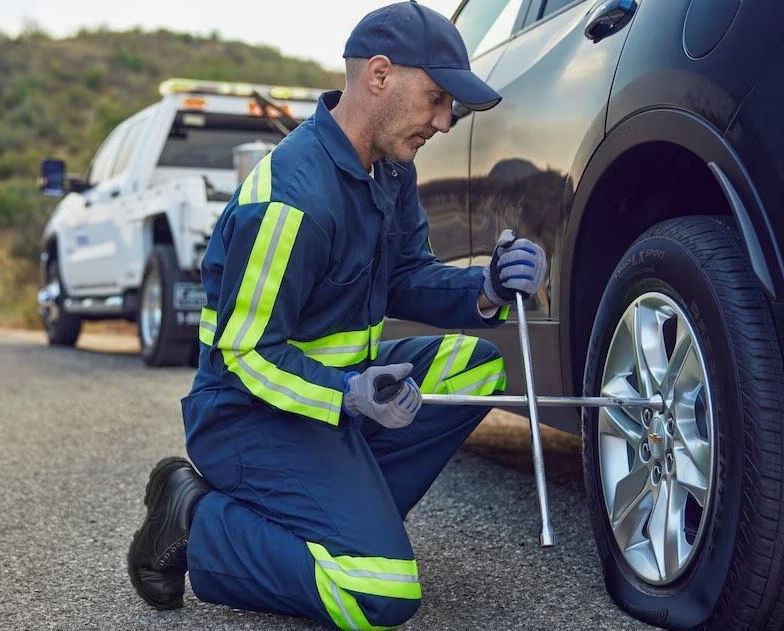 A man is changing a tire on a car on the side of the road.