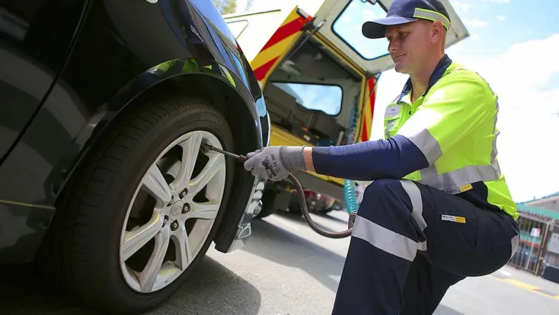 A man is changing a tire on a black car.