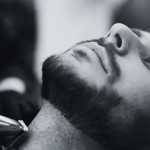 Man's face tilted back, being trimmed with a trimmer at a barber shop, close-up, at The Fade Brothers - Indianapolis, IN