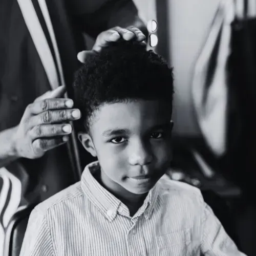 A young client receiving a precision haircut for textured hair at a professional barbershop in Indianapolis, highlighting the shop's family-friendly environment.