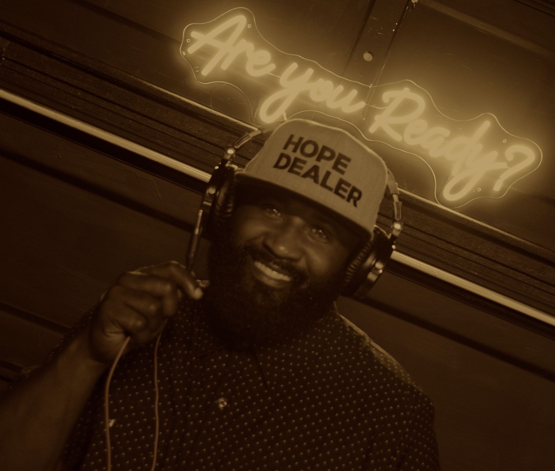 A man wearing headphones and a hat that says hope dealer
