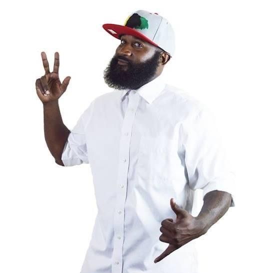 A man with a beard wearing a hat and giving a peace sign