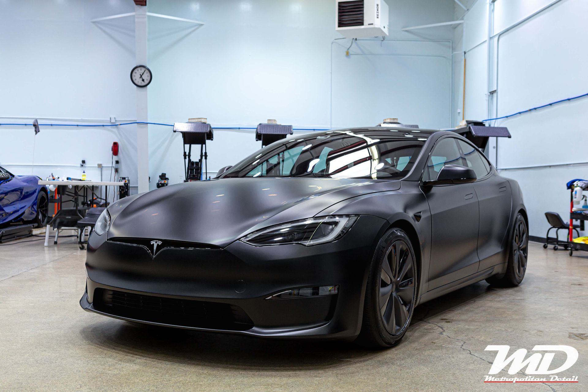 A black tesla model s is parked in a garage.