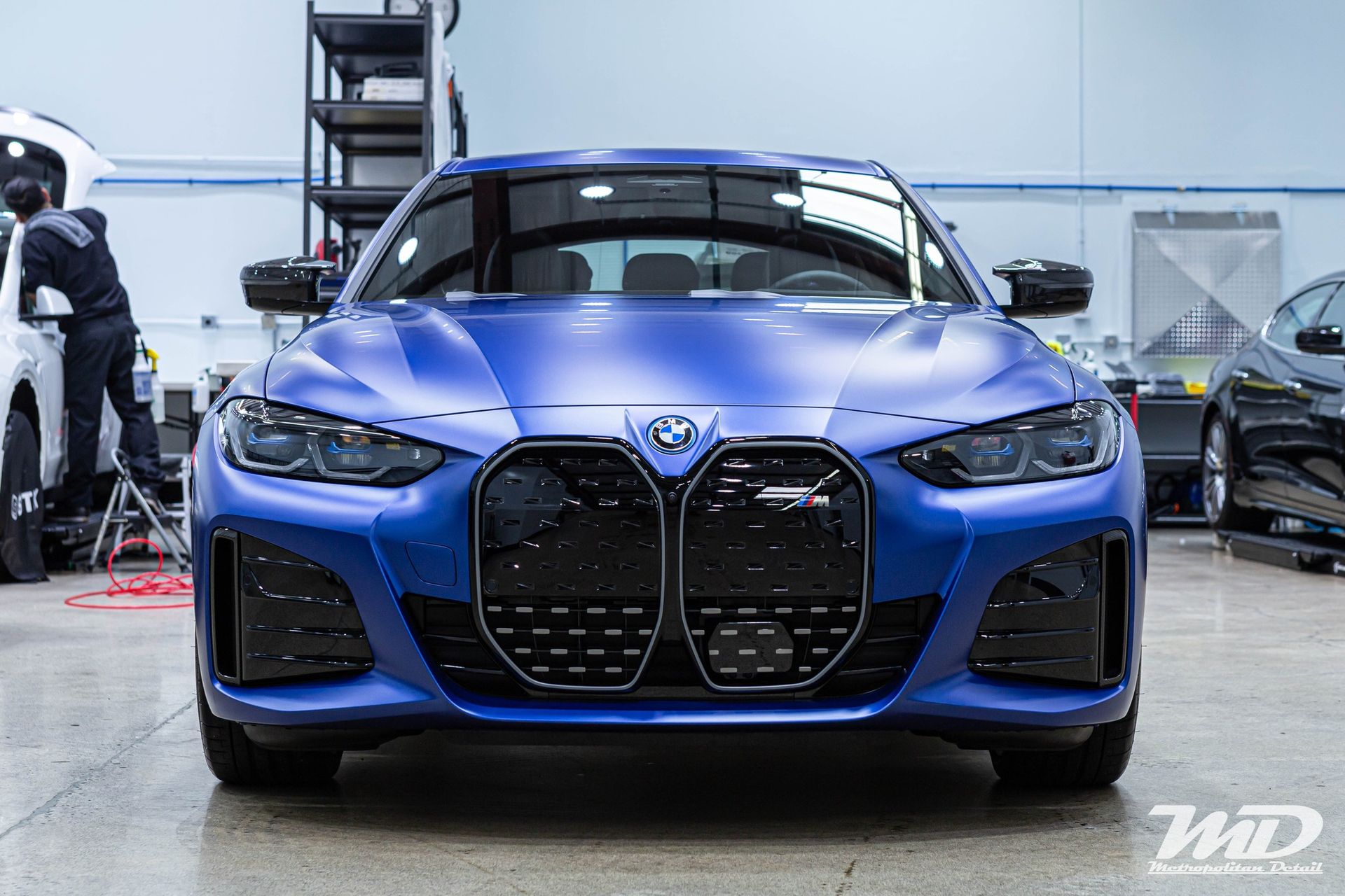 A blue bmw 4 series is being worked on in a garage.