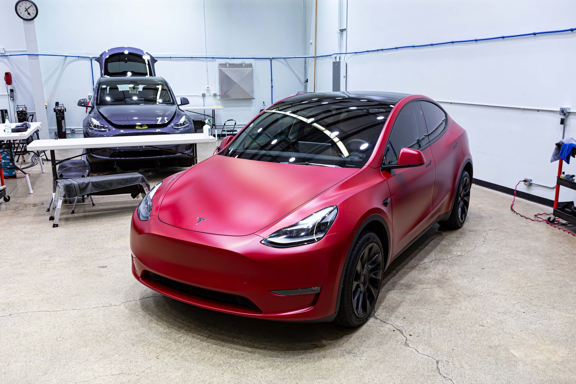 A red tesla model y is parked in a garage.