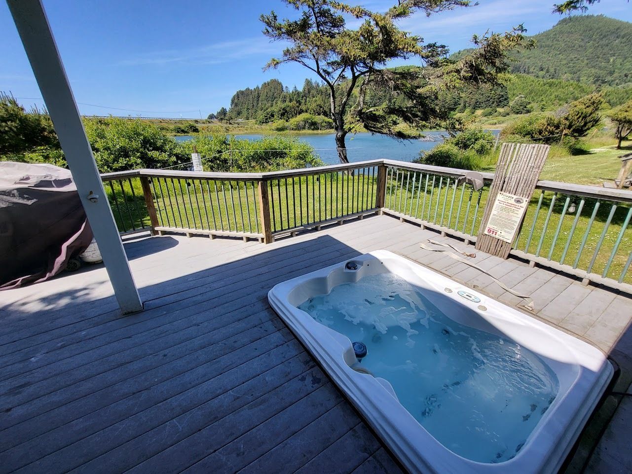 Deck with a hot tub overlooking a green river valley under a blue sky