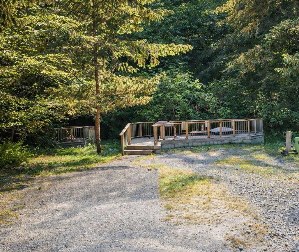 Gravel path leading to a small wooden hot tub deck in a wooded park