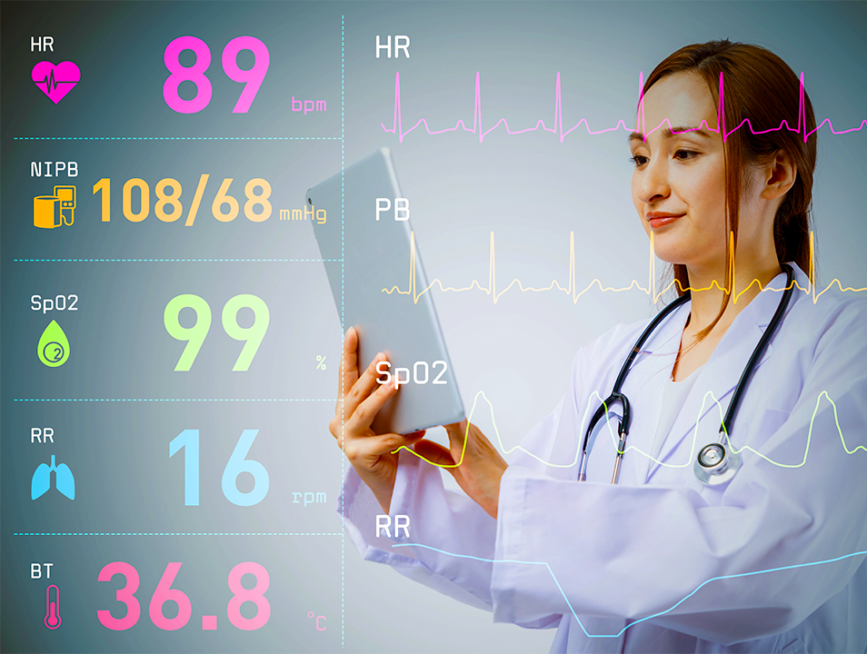 Female ACLS doctor examining vital signs on a tablet, next to a medical monitor displaying patient data.