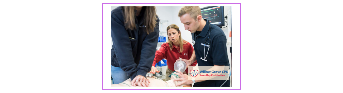 Two students providing CPR on a manikin with the guidance of a BLS instructor in the background. One student is giving chest compressions while the other is providing ventilations with a bag mask device. The Willow Grove CPR logo is visible in the image