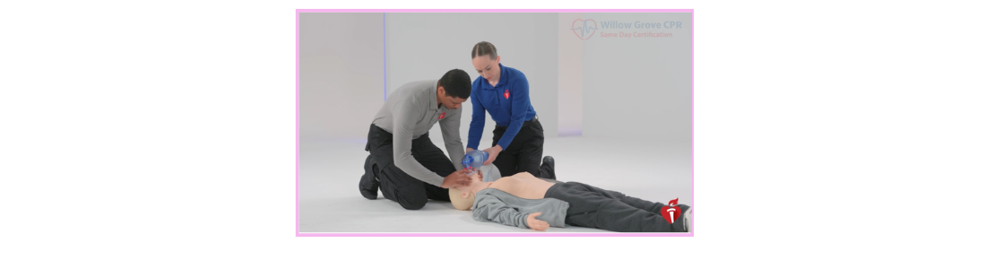 Two people kneeling next to a medical mannequin on the floor, performing CPR compressions and using a bag valve mask.