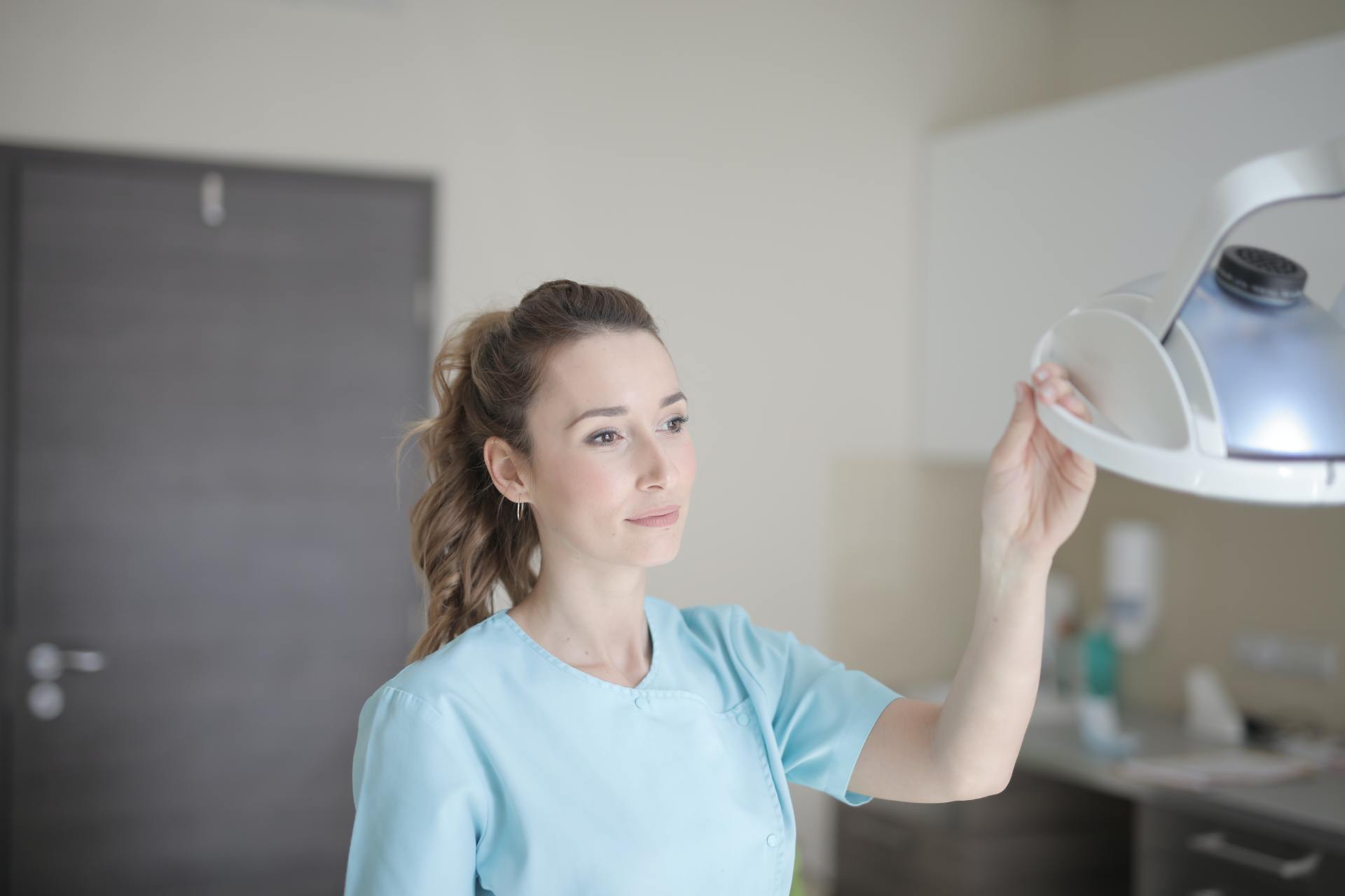 a female dentist is adjusting a light in a dental office .