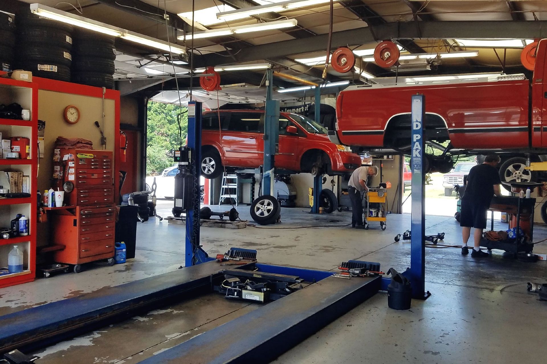 A red truck is on a lift in a garage