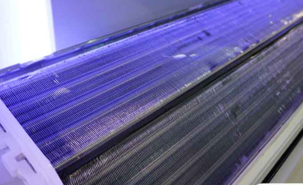 A close up of an air conditioner with a purple light on it.