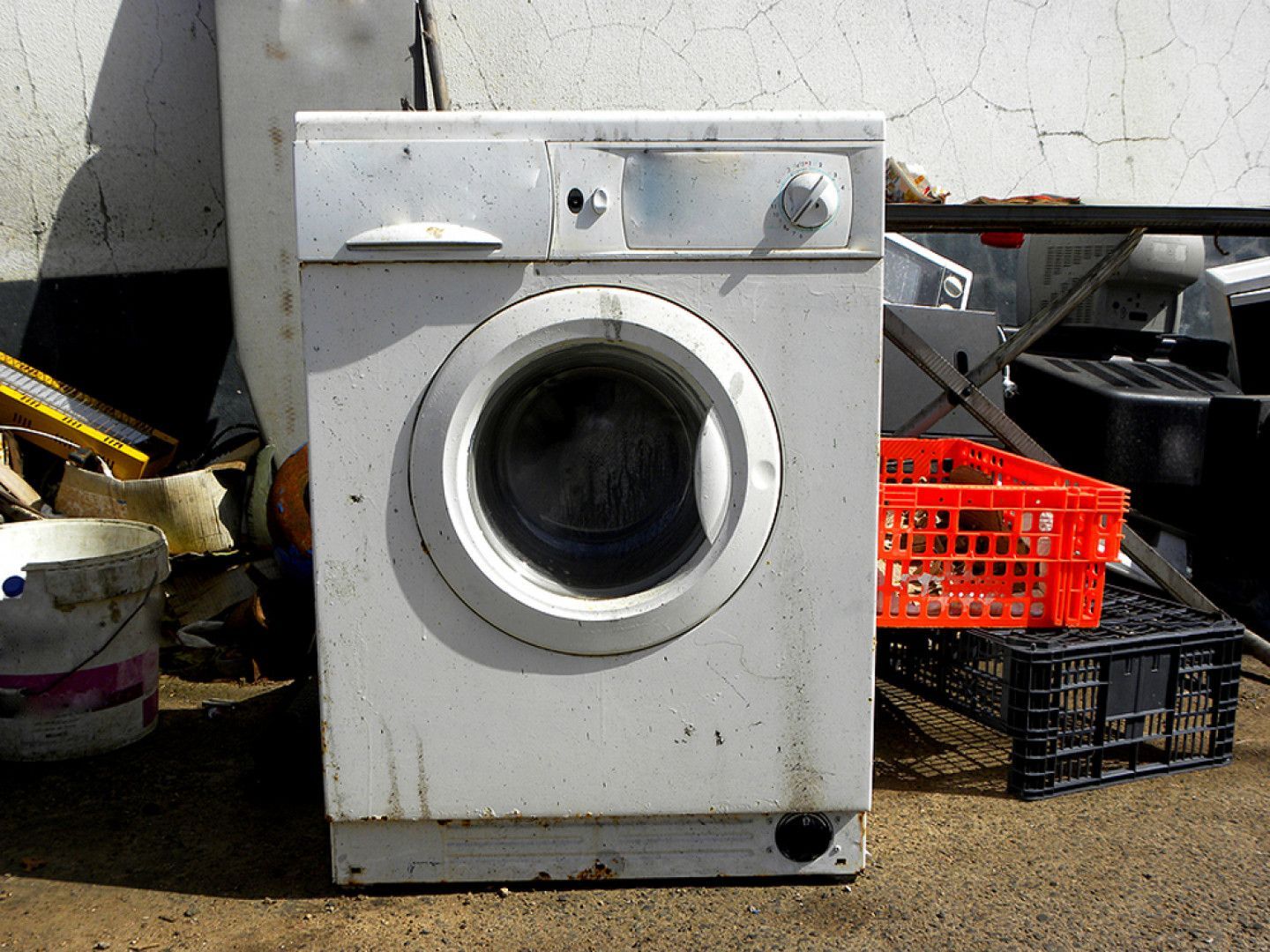 A white washing machine is sitting in a pile of junk