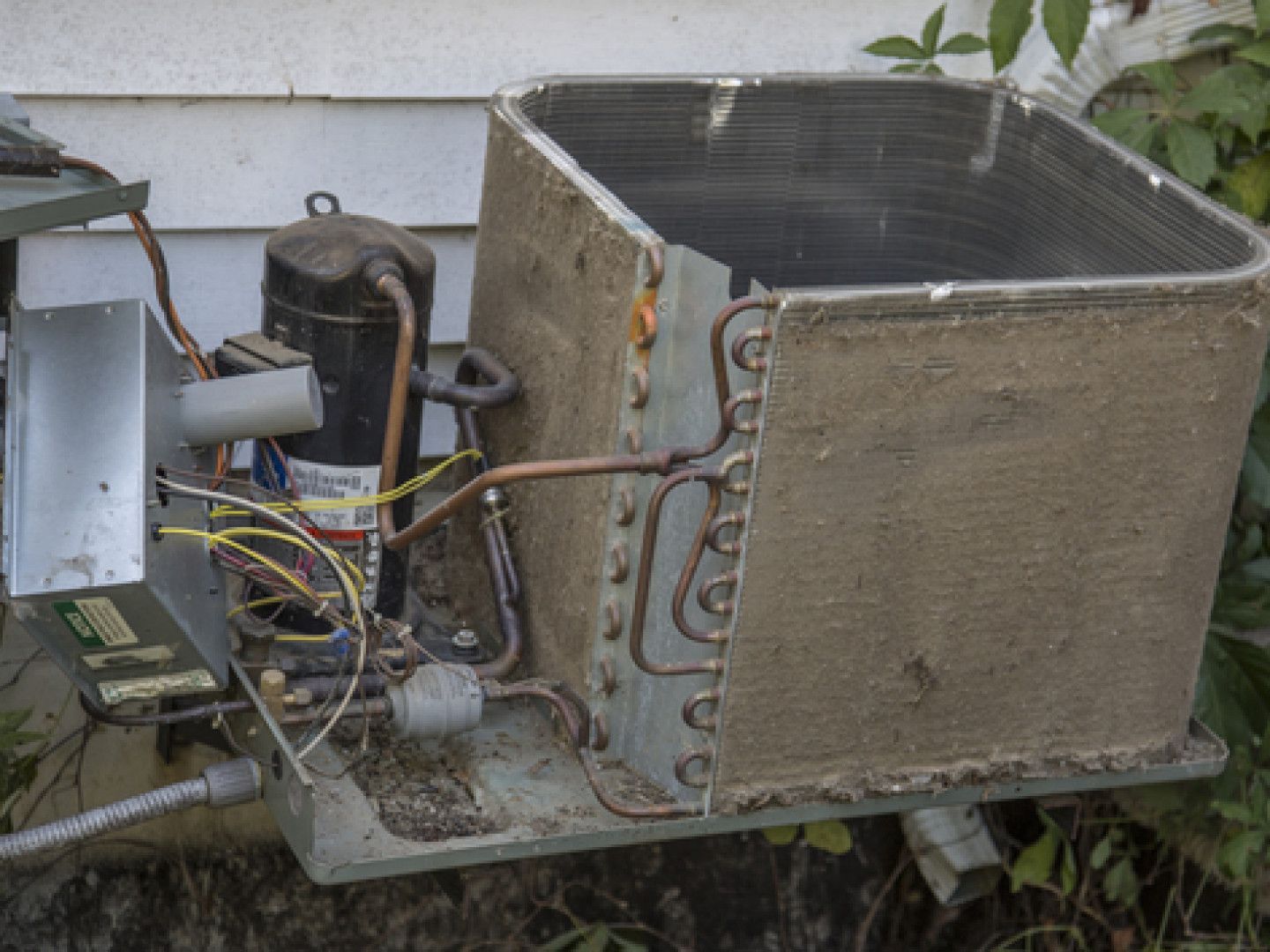 A dirty air conditioner is sitting outside of a house.