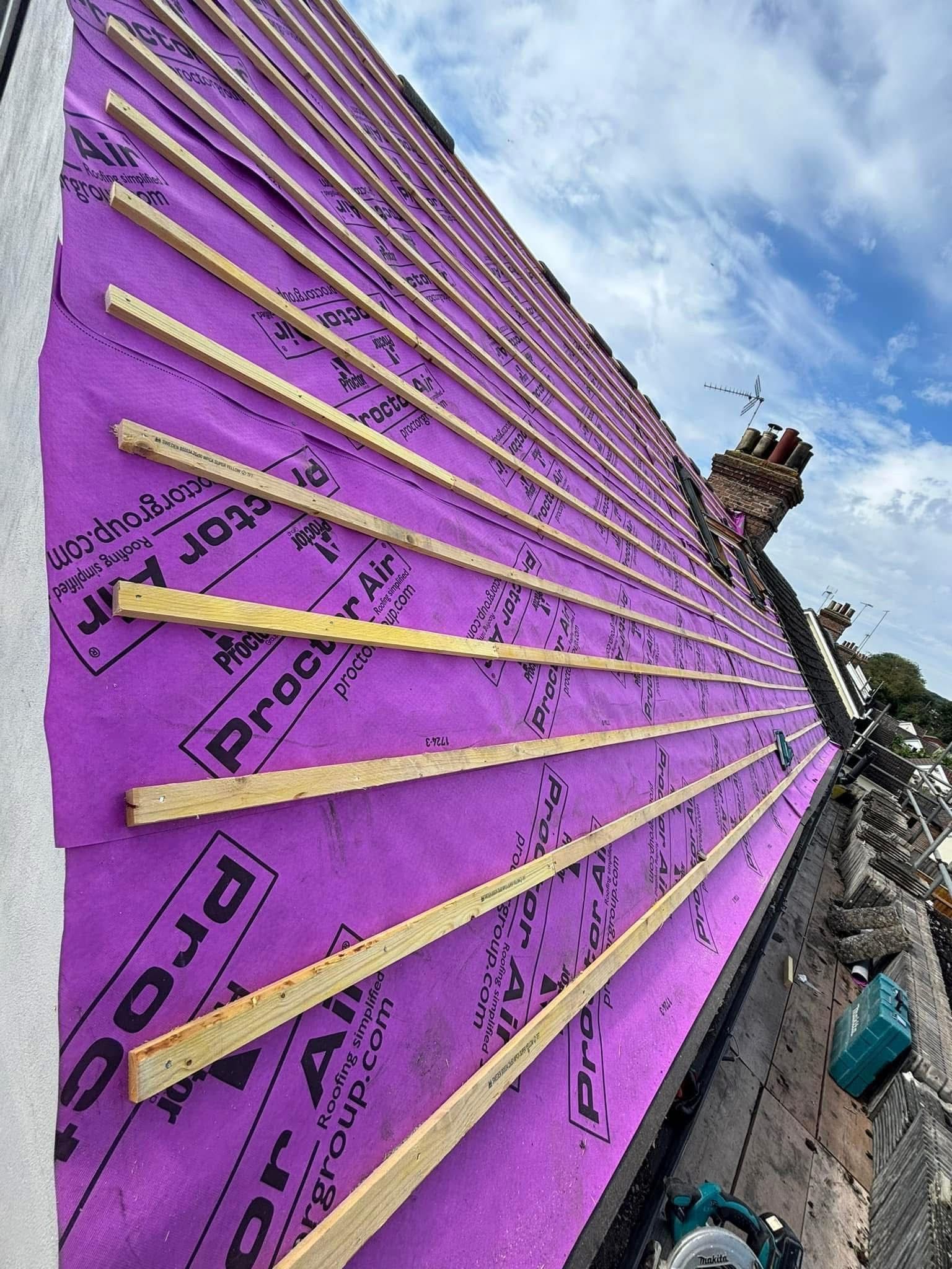 Purple roofing underlayment with wood battens on a sloped roof.