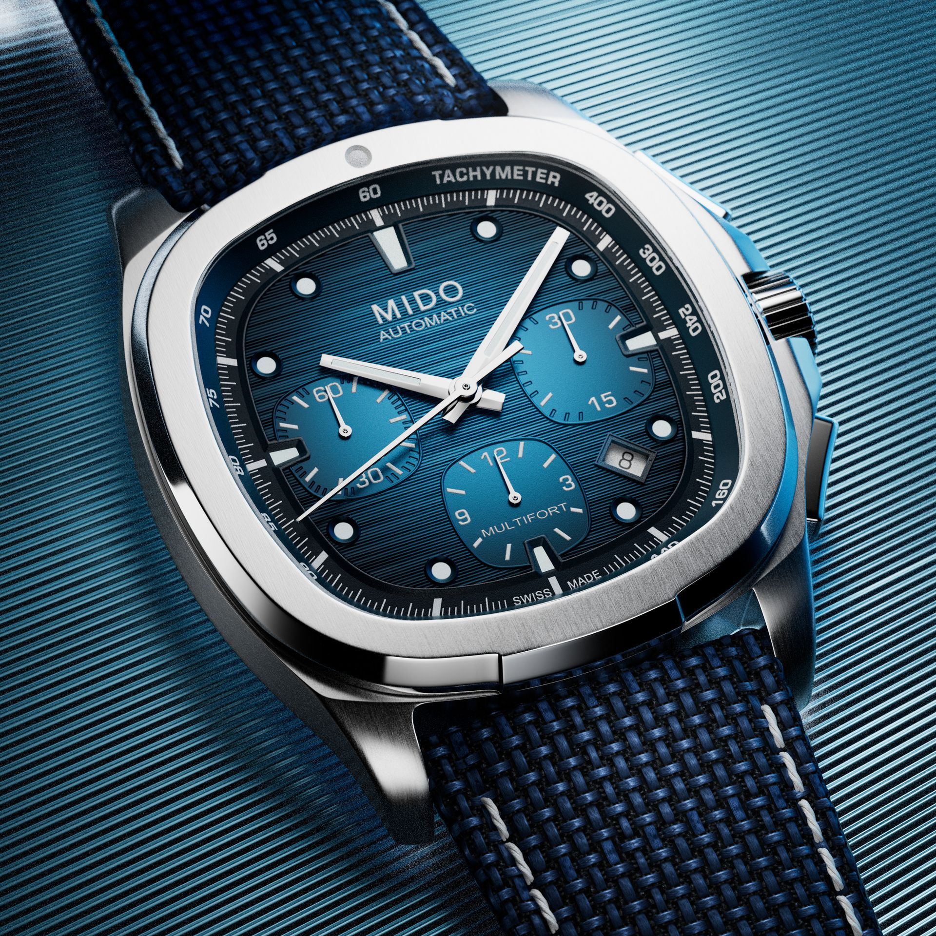 Orologio cronografo Blue Mido con cinturino blu navy su sfondo in tessuto blu testurizzato.