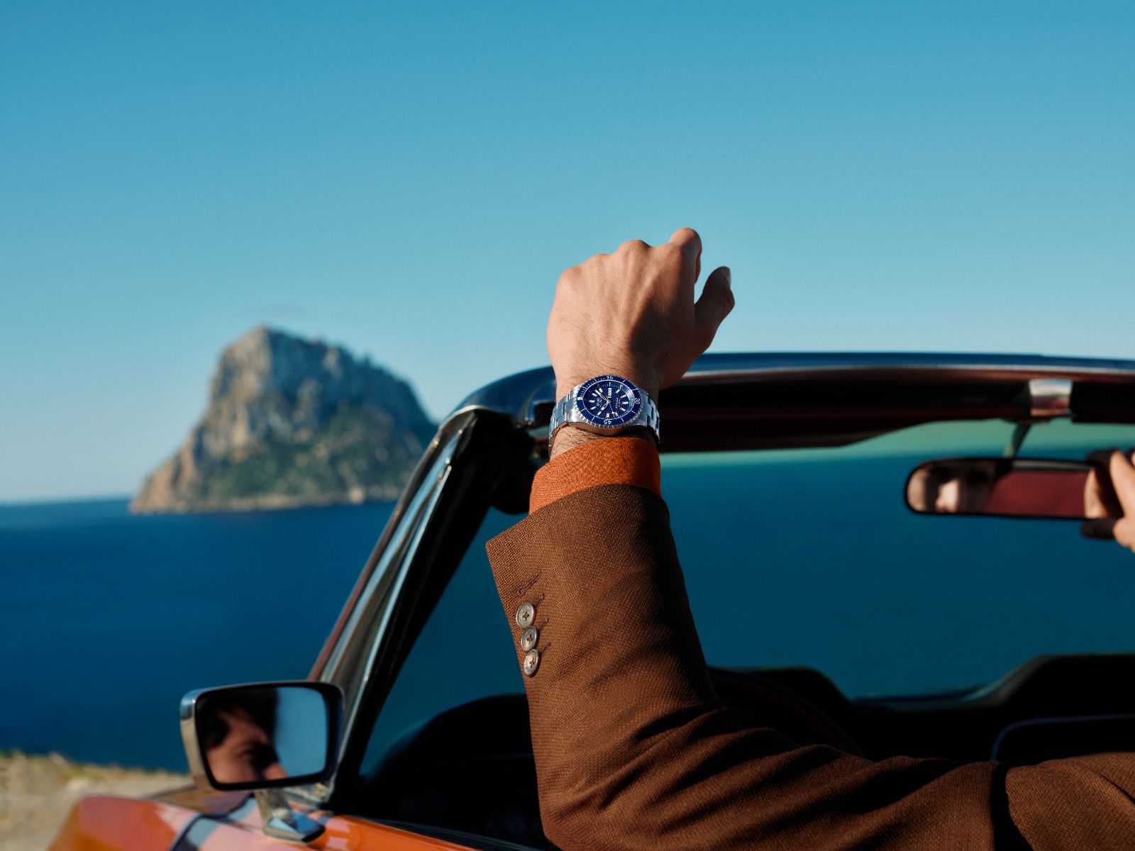 Pubblicità di MIDO che mostra tre orologi di lusso su uno sfondo di tessuto beige, con la scritta del marchio in arancione sulla sinistra.