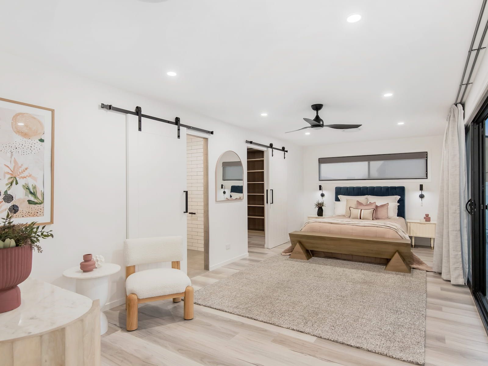 A bedroom with a bed , chair , table and sliding barn door.