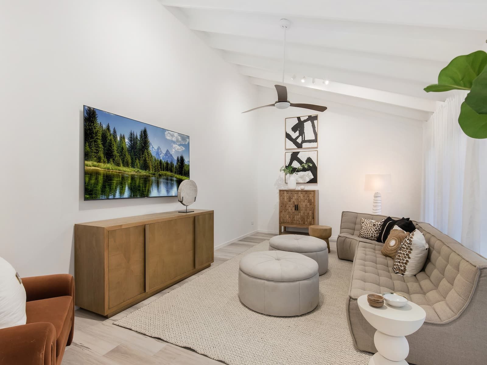 A living room with a couch , chairs , ottomans and a flat screen tv.