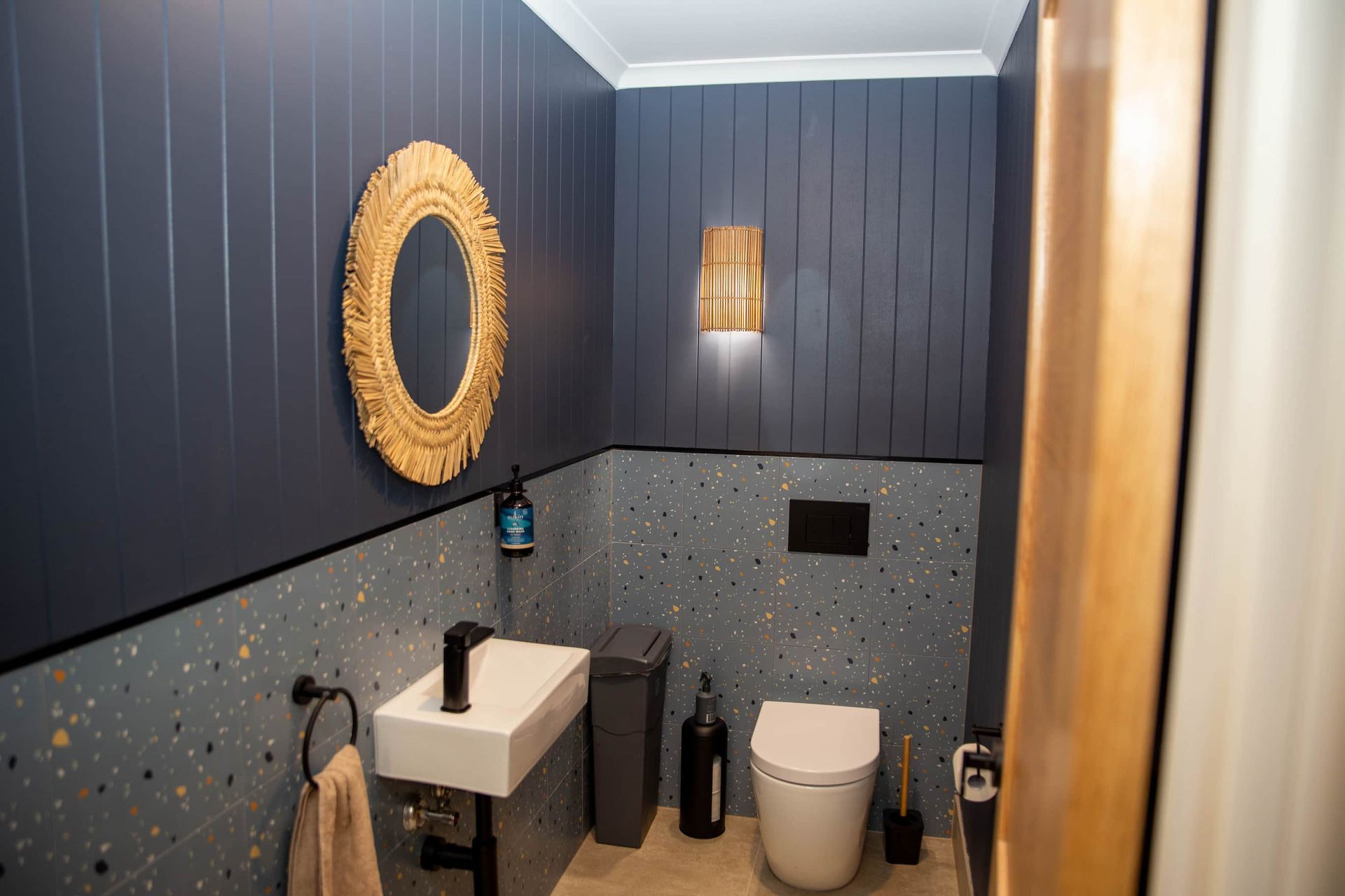 a bathroom with a toilet, sink, mirror and light.