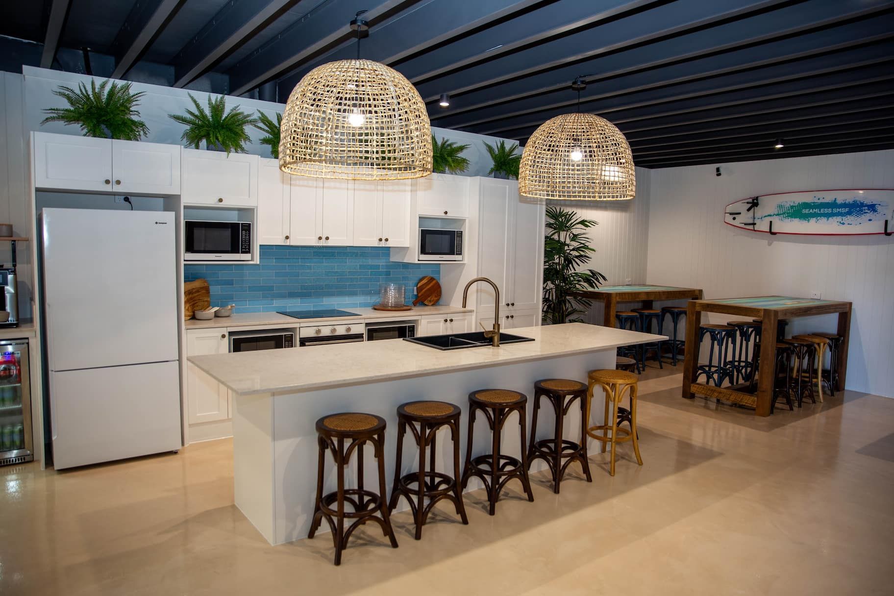 Modern kitchen with island, white cabinets, and woven pendant lights.
