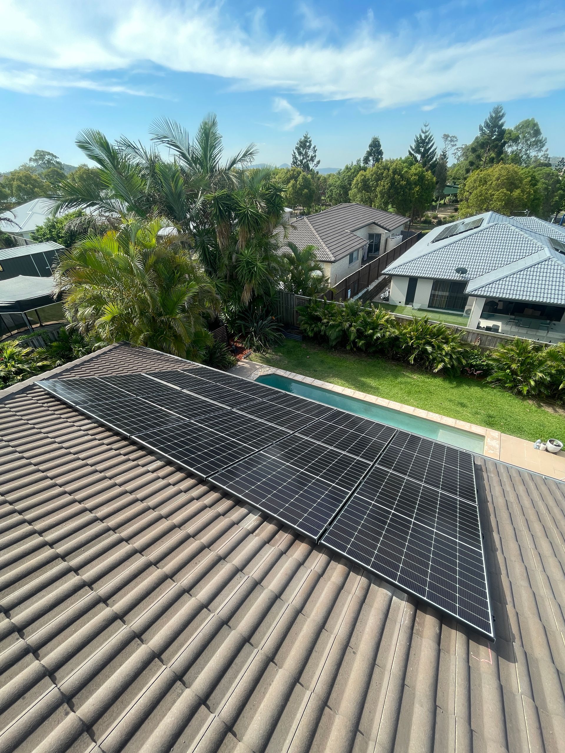A roof with solar panels on it and a pool in the background.