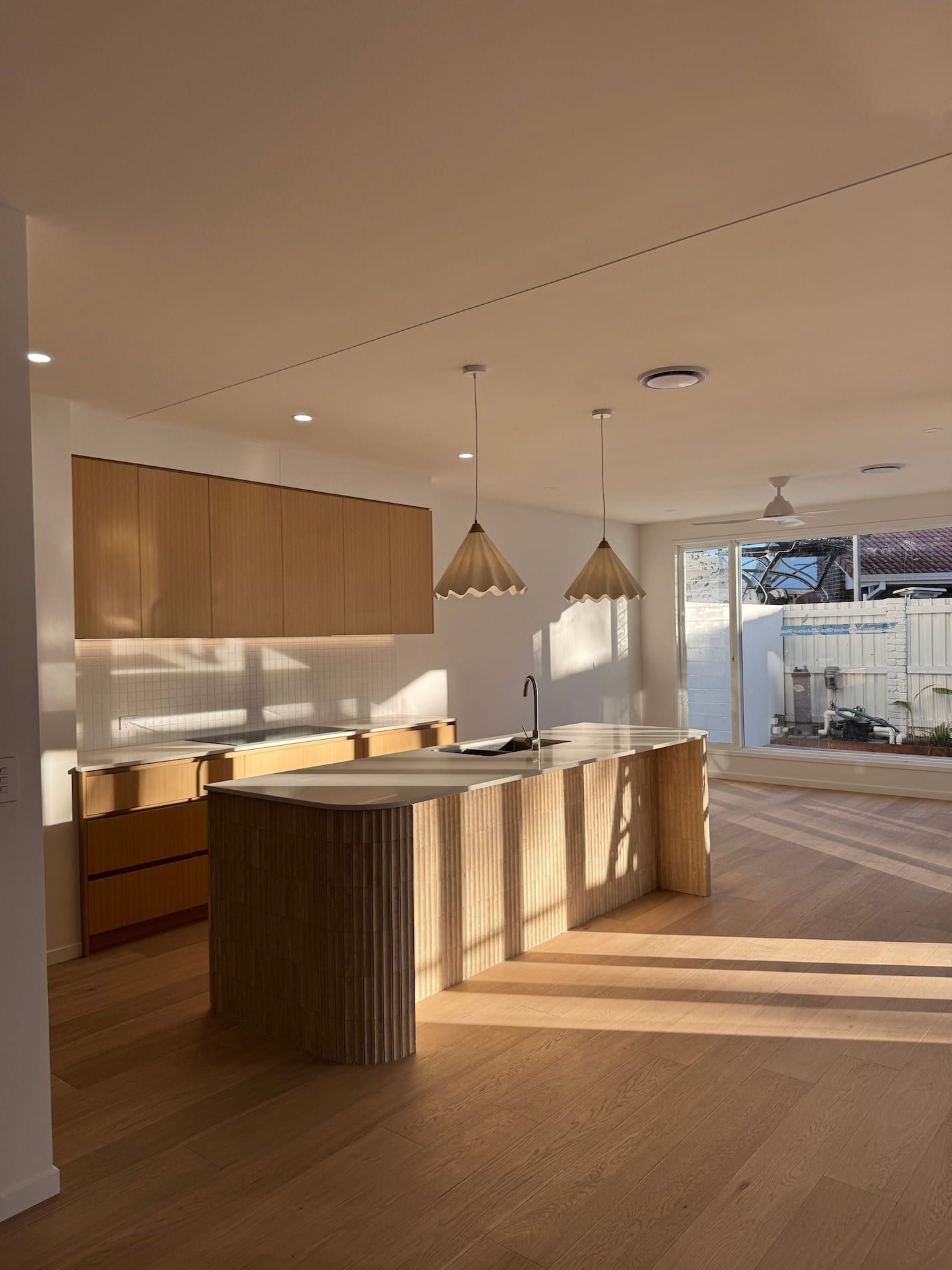 Modern kitchen with wood cabinets and island. Natural light floods the space.