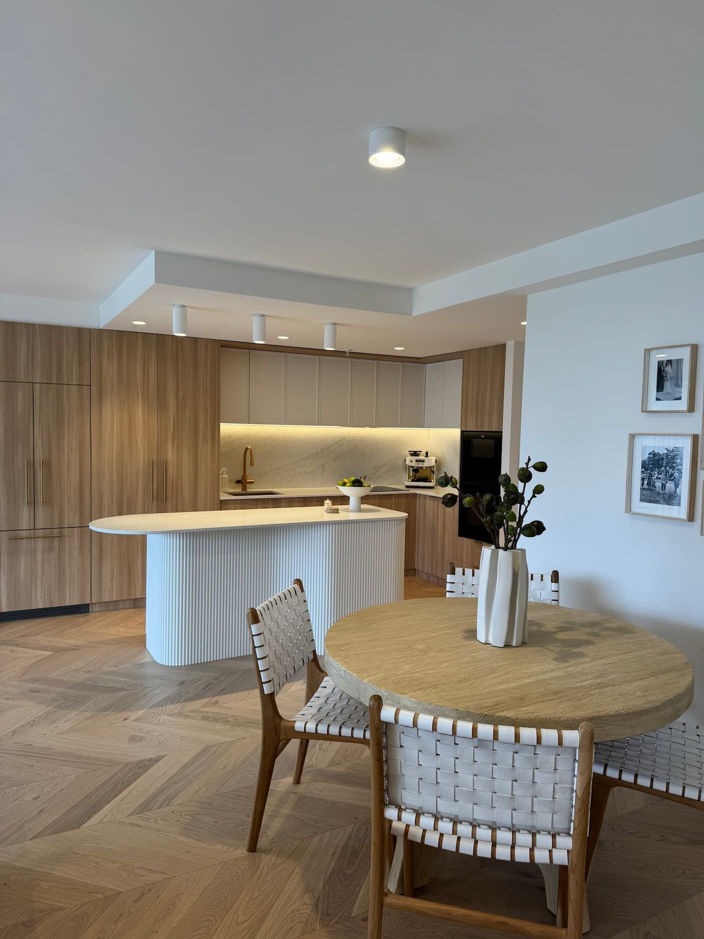 Modern kitchen and dining area with wooden cabinets, a unique island, and a round table.