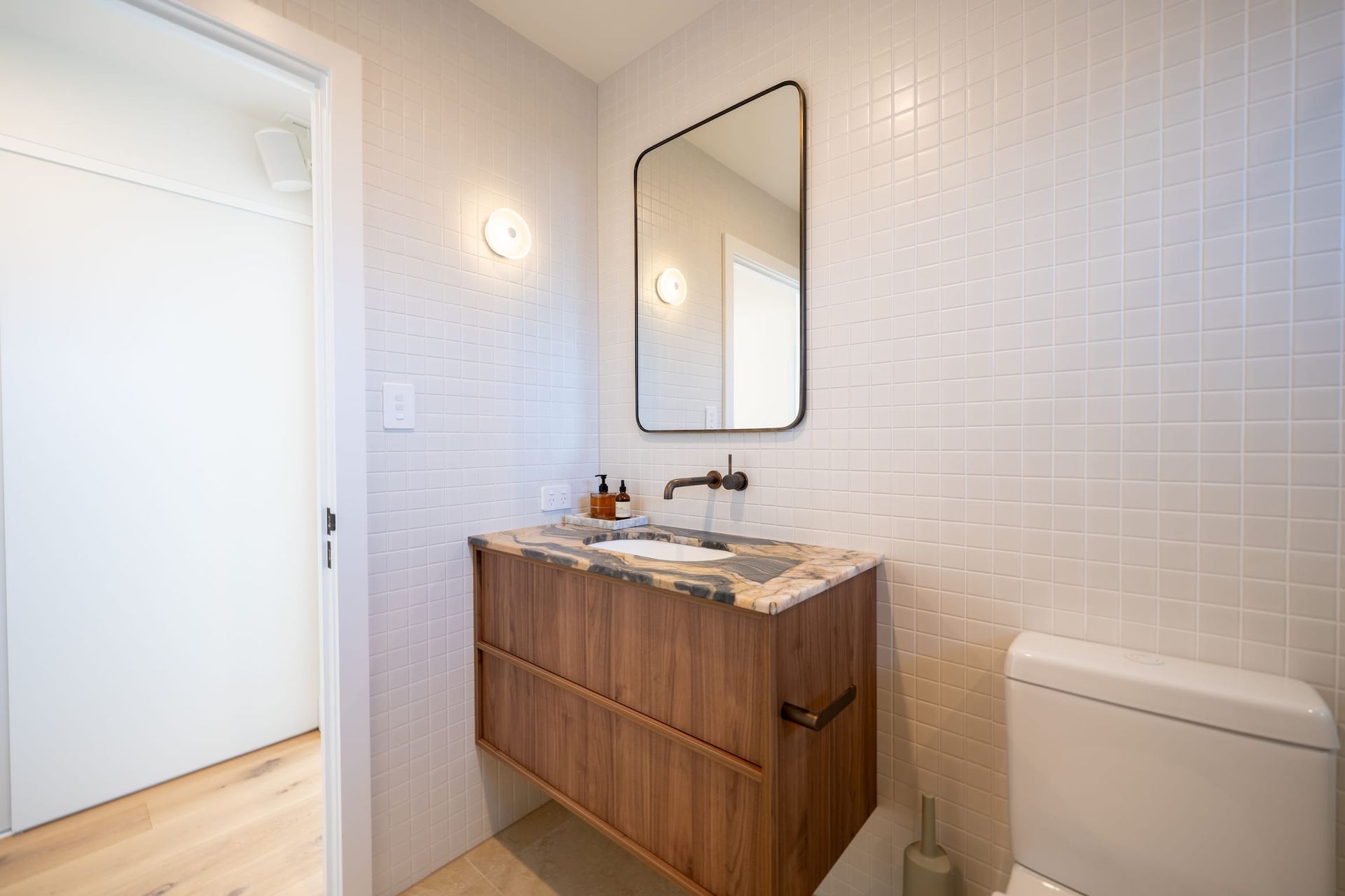 Small bathroom with a wood vanity, tiled walls, and a rectangular mirror.