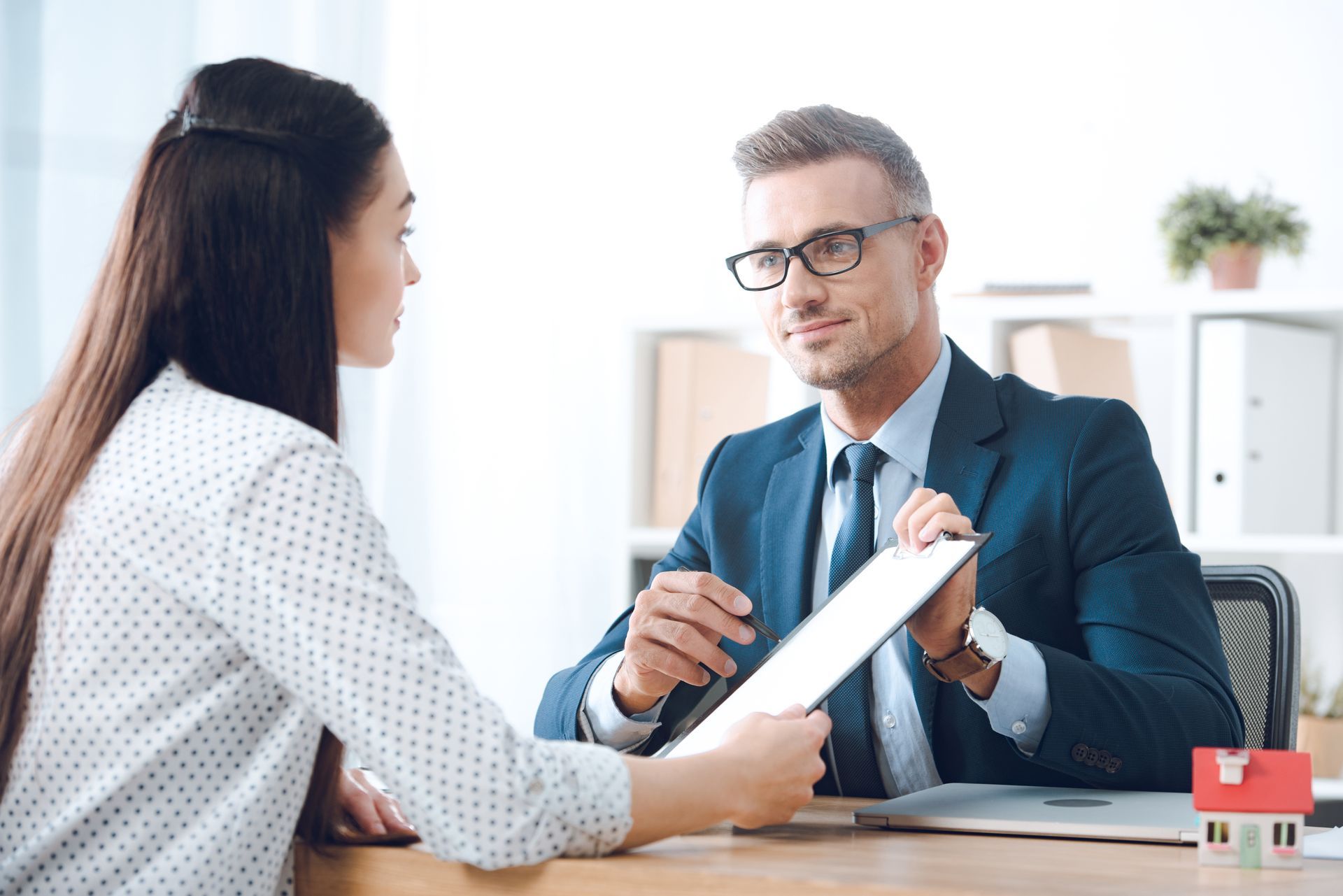 An insurance agent in a suit reviewing a policy document with a business owner An insurance agent in a suit reviewing a policy document with a business owner