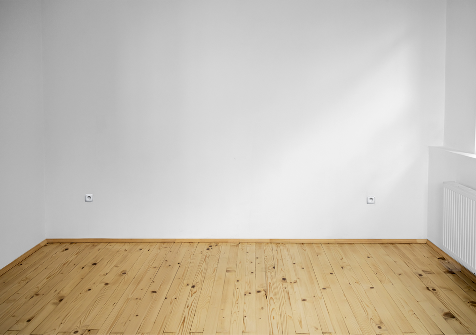 An empty room with a wooden floor and white walls.