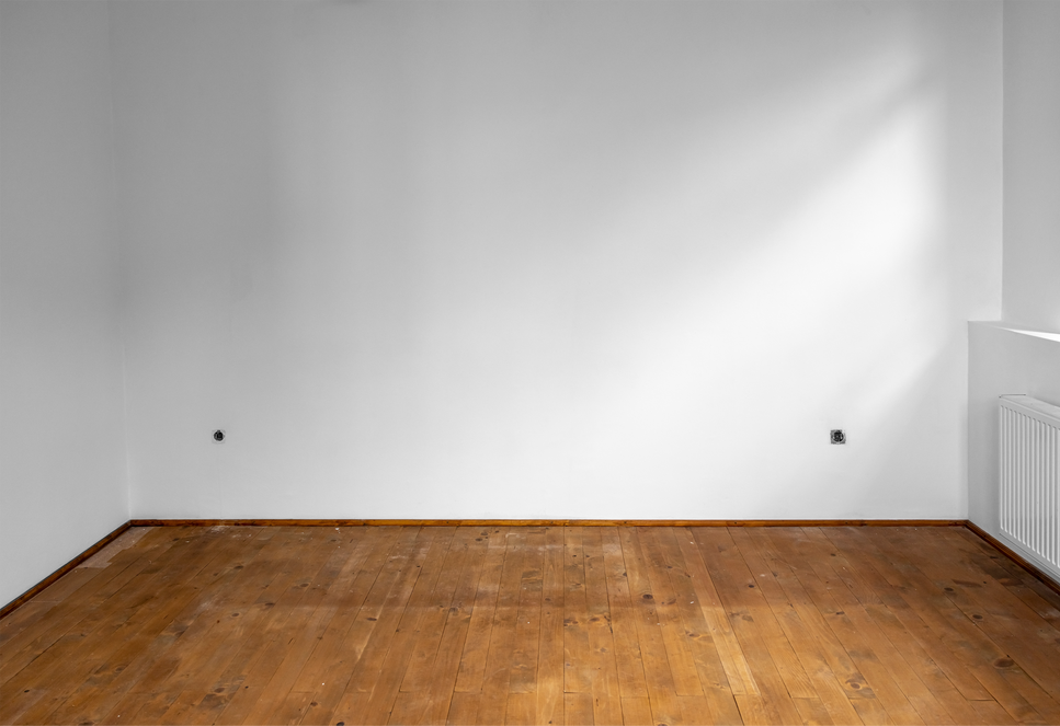 An empty room with a wooden floor and white walls.