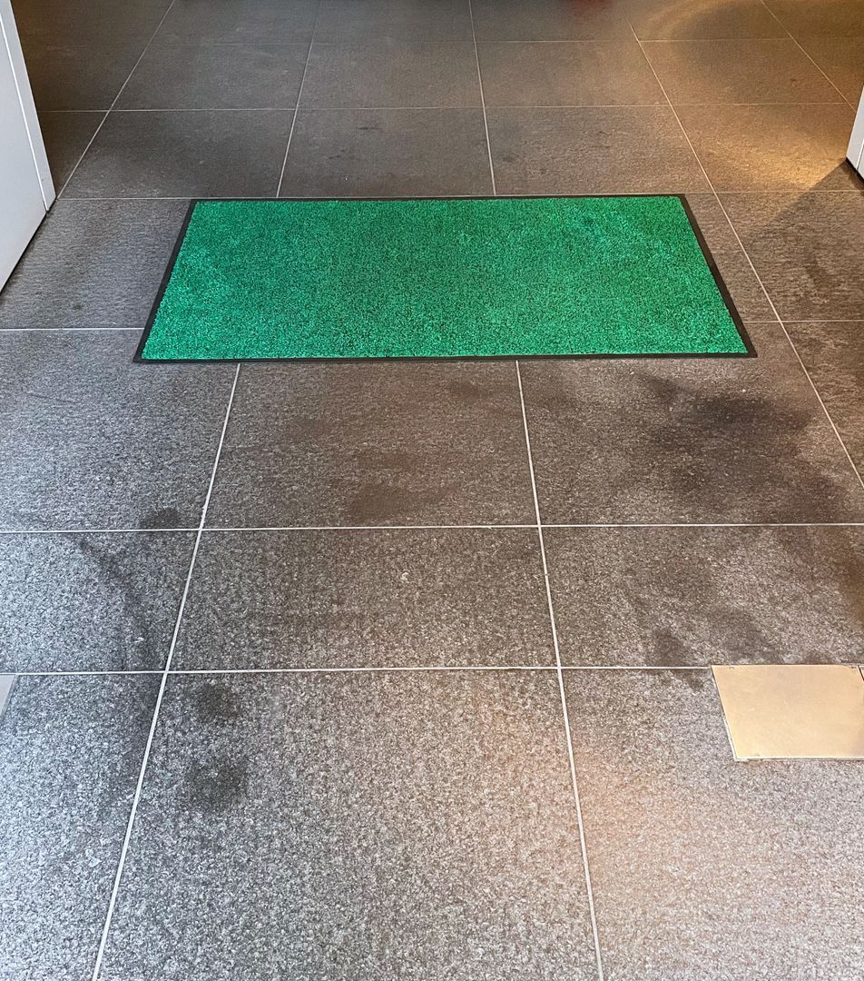 A green mat is sitting on a tiled floor.