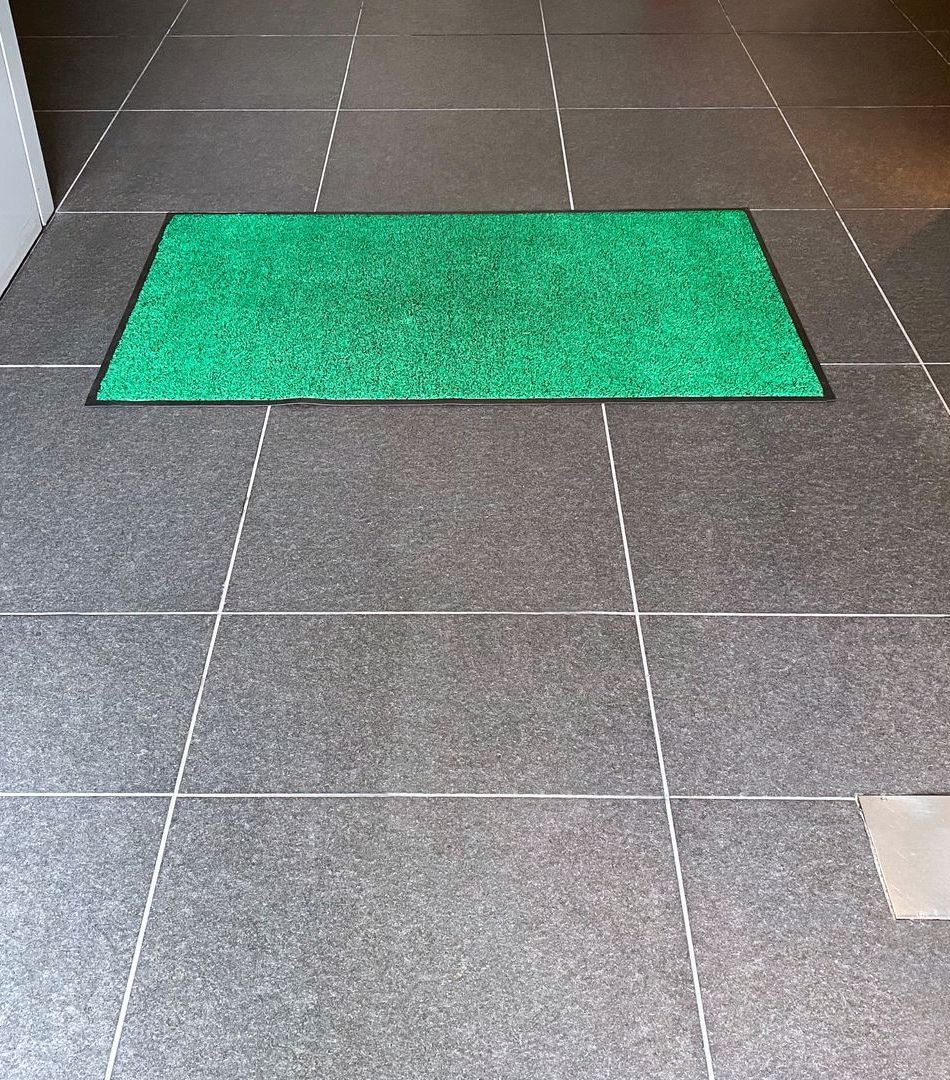 A green mat is sitting on a tiled floor.