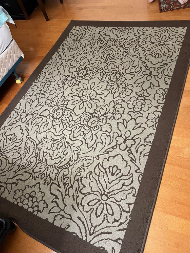 A rug with a floral pattern on it is on a wooden floor.