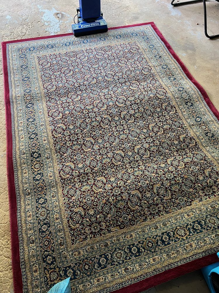 A rug is sitting on the floor next to a vacuum cleaner.