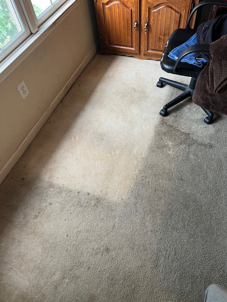 A room with a carpeted floor , a chair and a window.