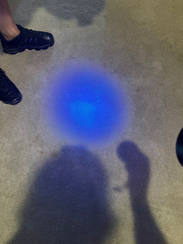 A person is standing next to a blue light on the floor.