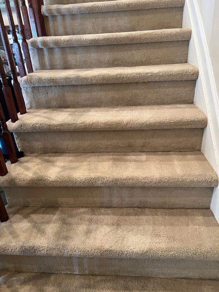 A set of stairs with carpeted steps and a wooden railing.
