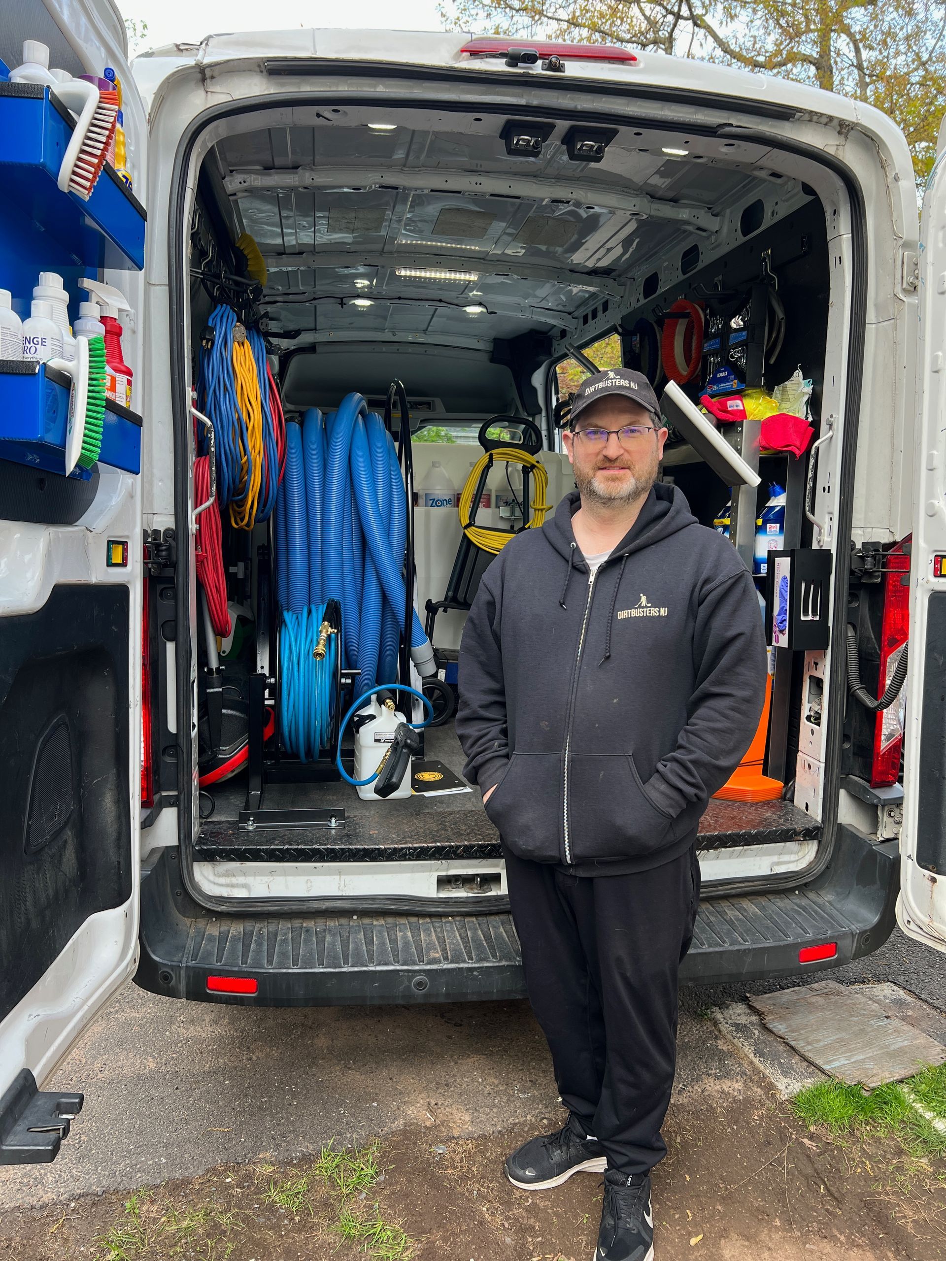 A man is standing in front of a van filled with tools.
