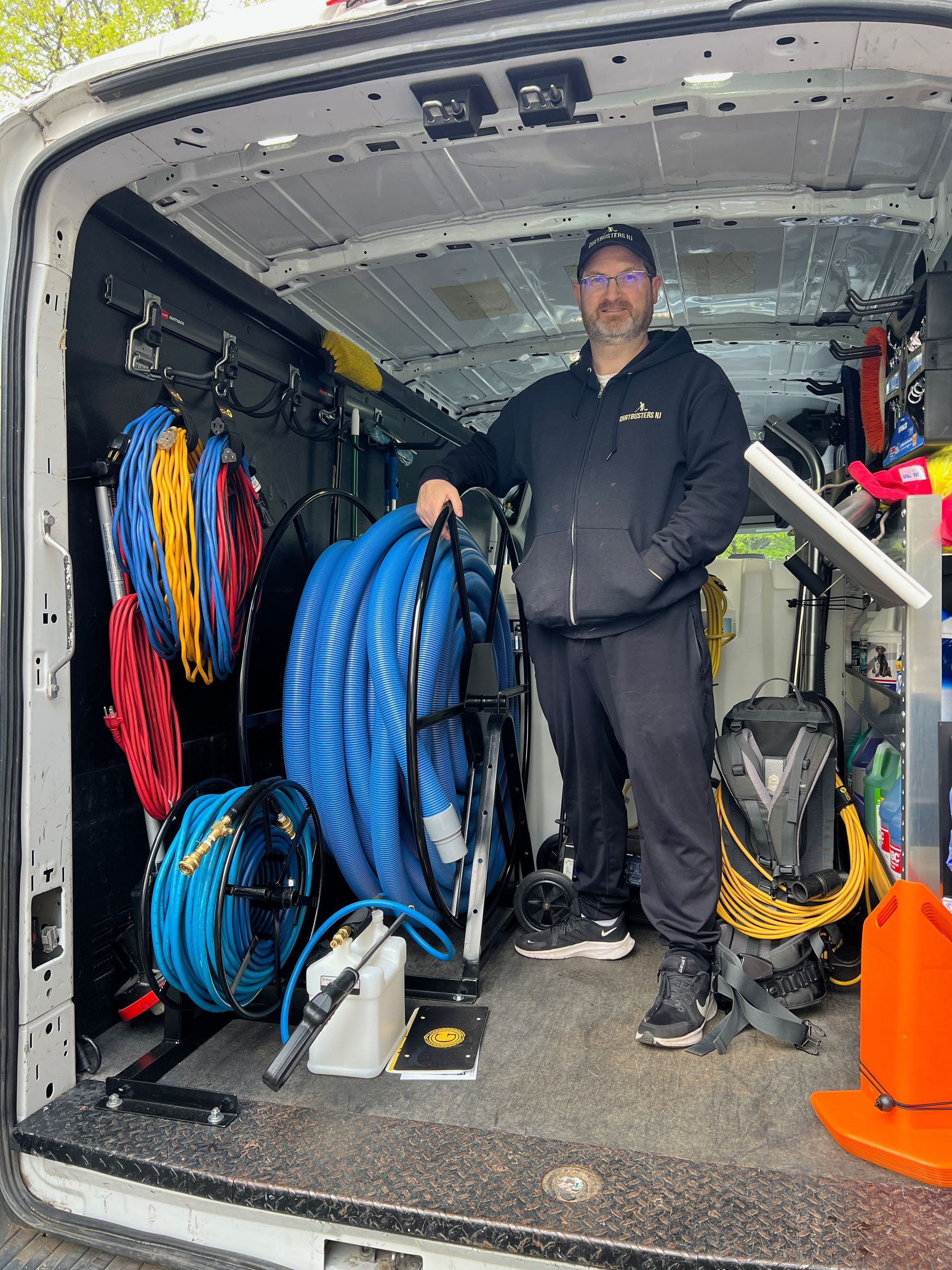 A man is standing in the back of a van filled with tools.