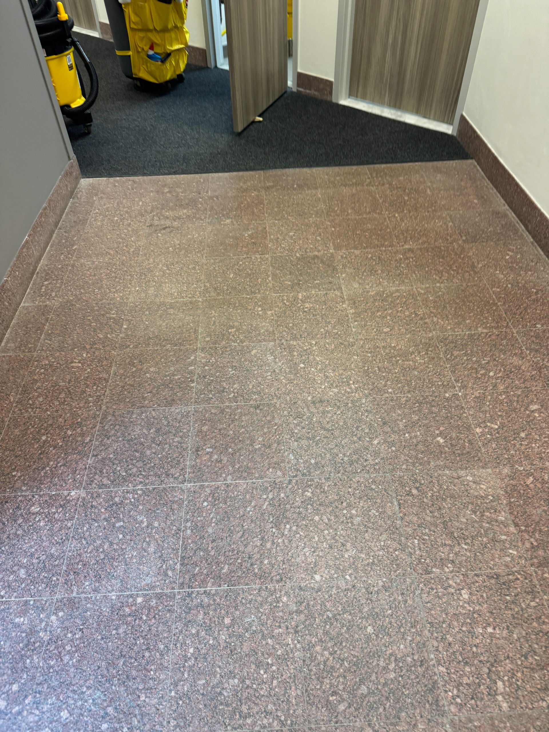 A brown floor in a hallway next to a door.