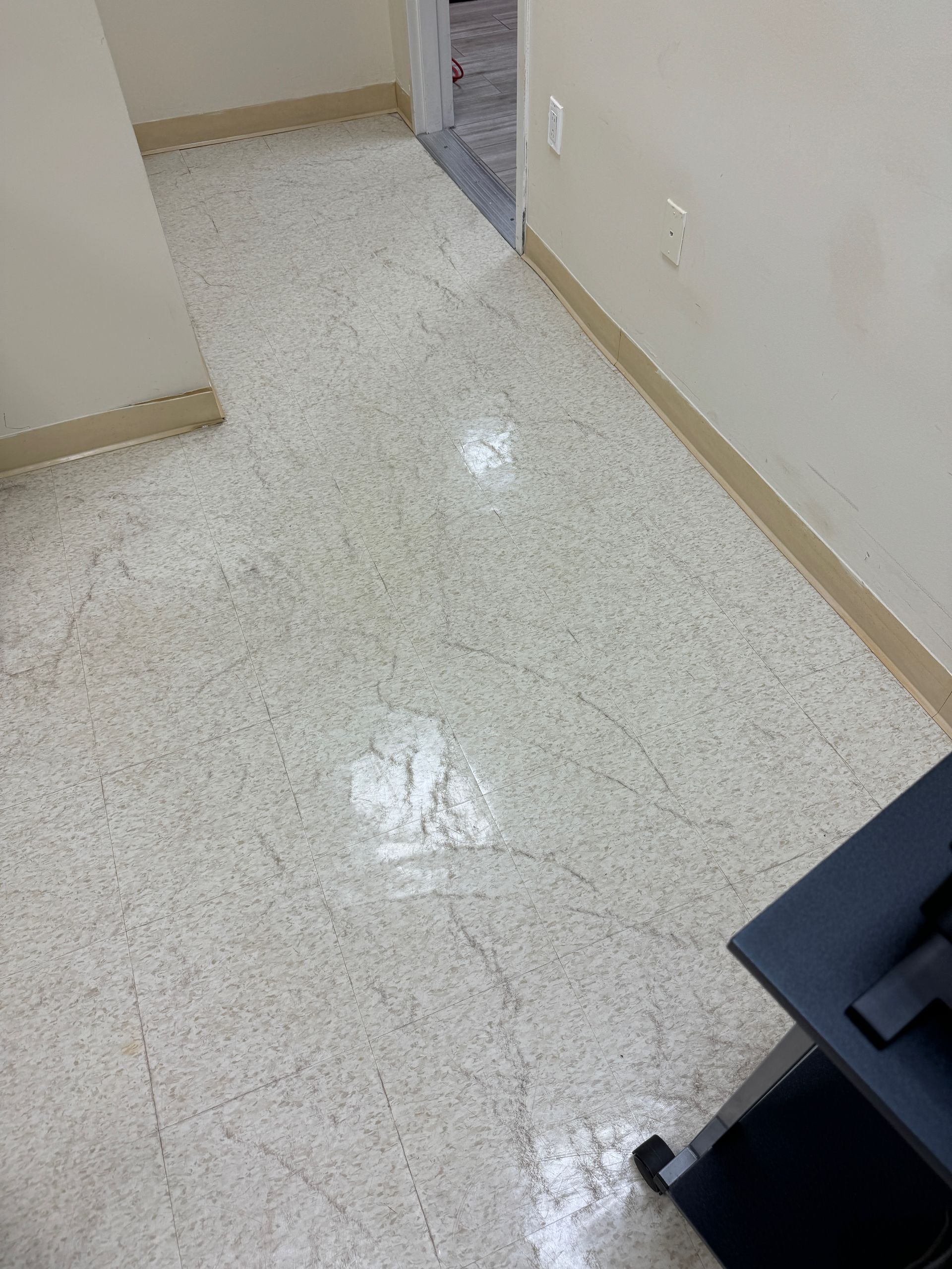 A white tile floor in a room next to a door.