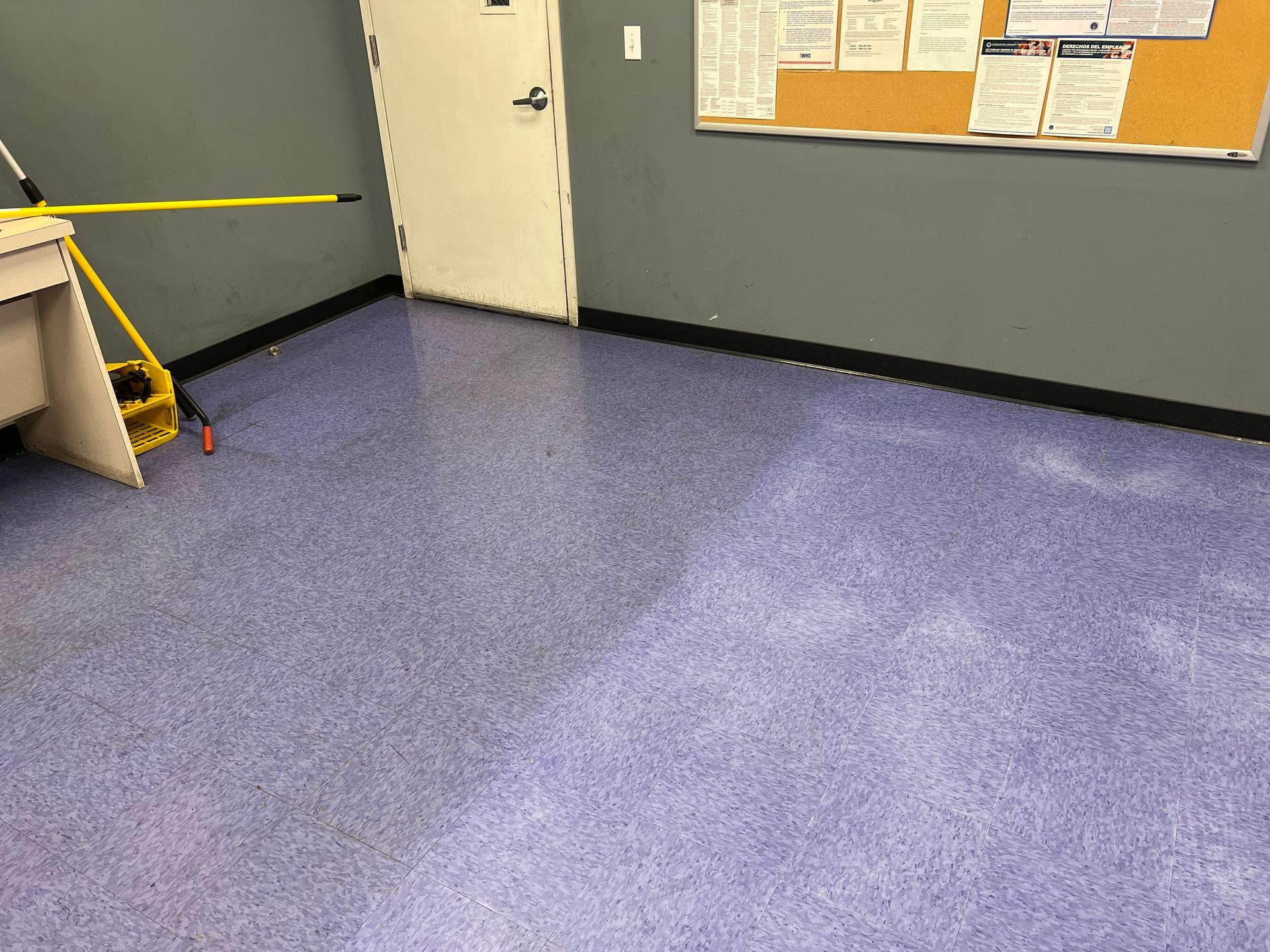 A room with a purple floor and a yellow mop.